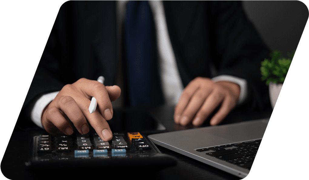 Man using calculator and laptop at desk.
