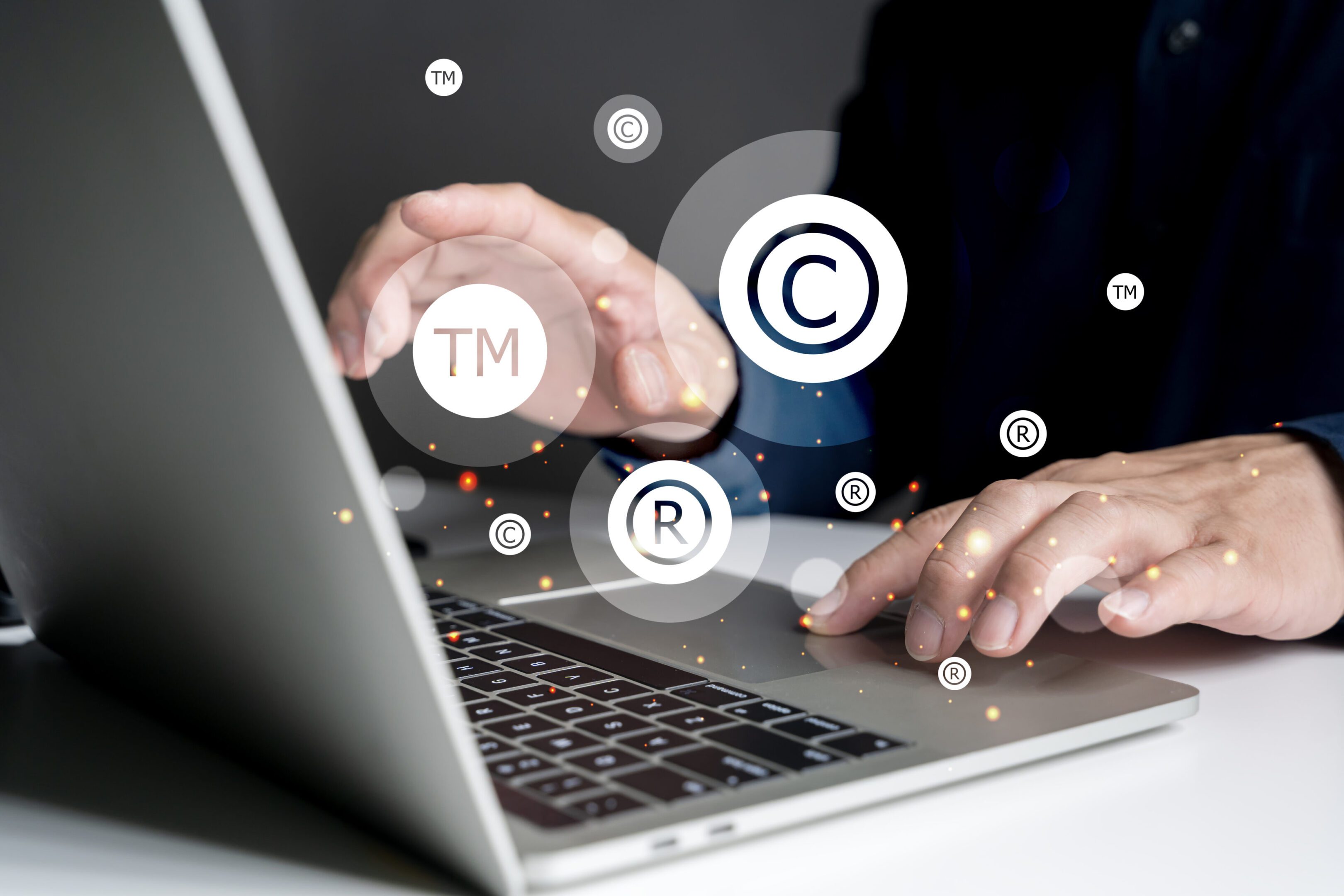 Hands typing on laptop with copyright symbols.